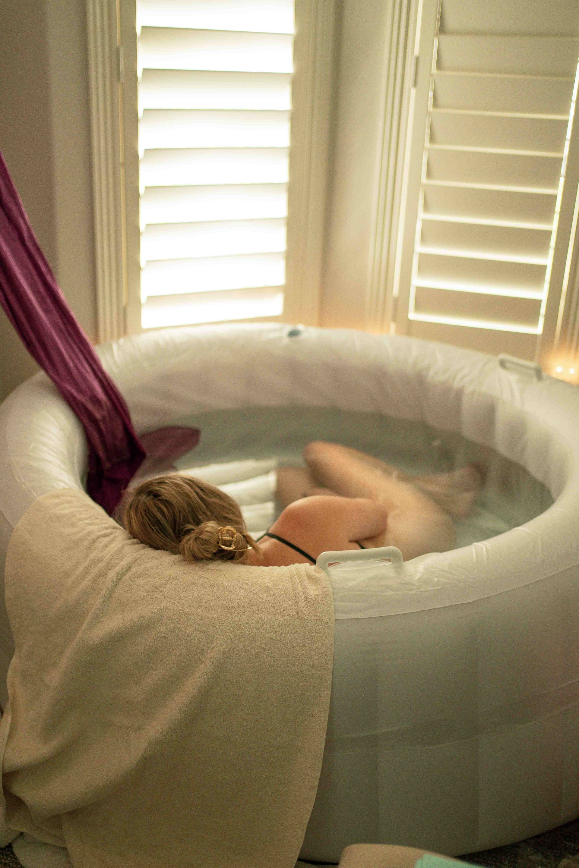 Peaceful water birth scene with natural light streaming through windows